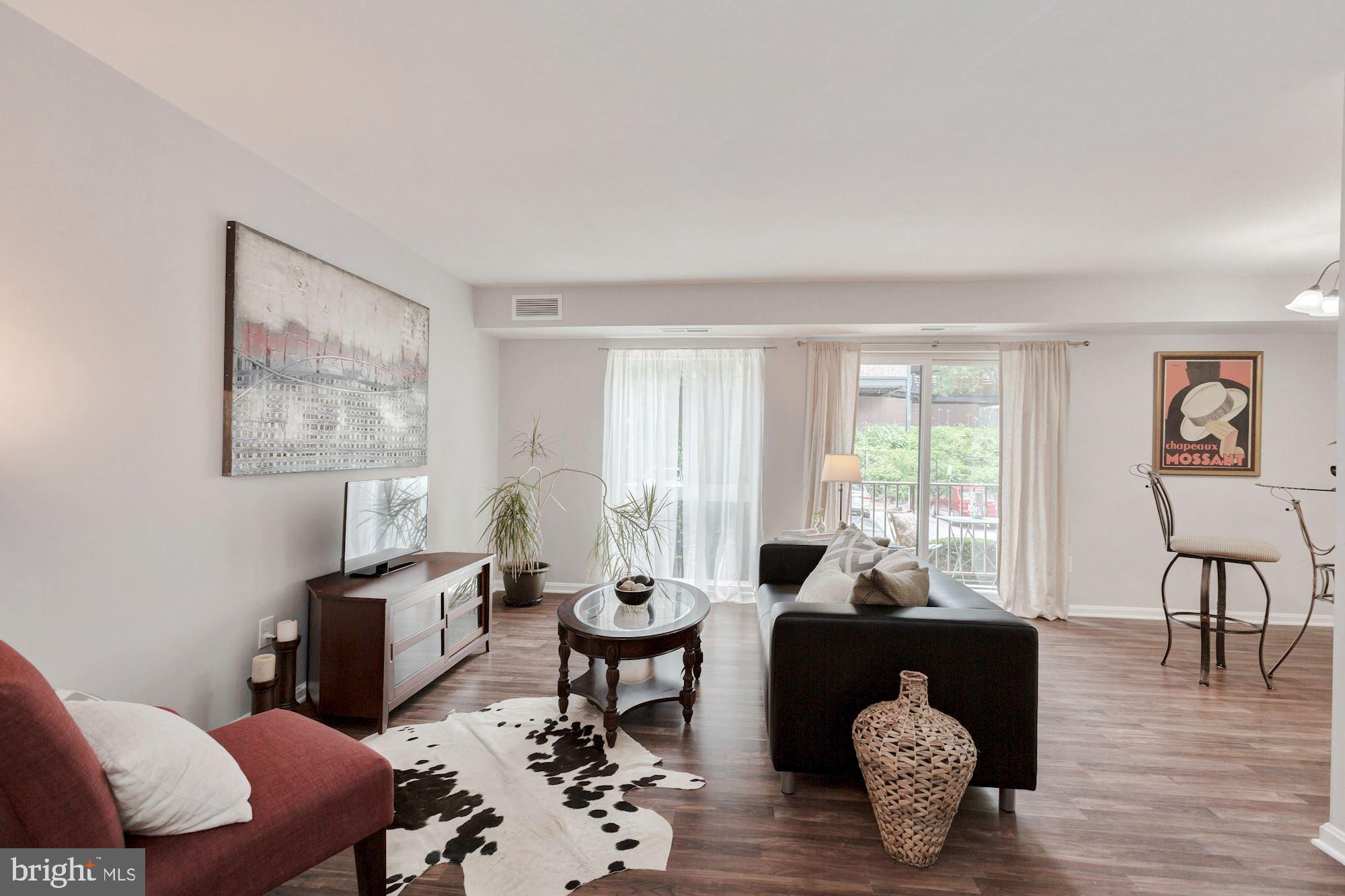 a living room with furniture a rug a lamp and a large window