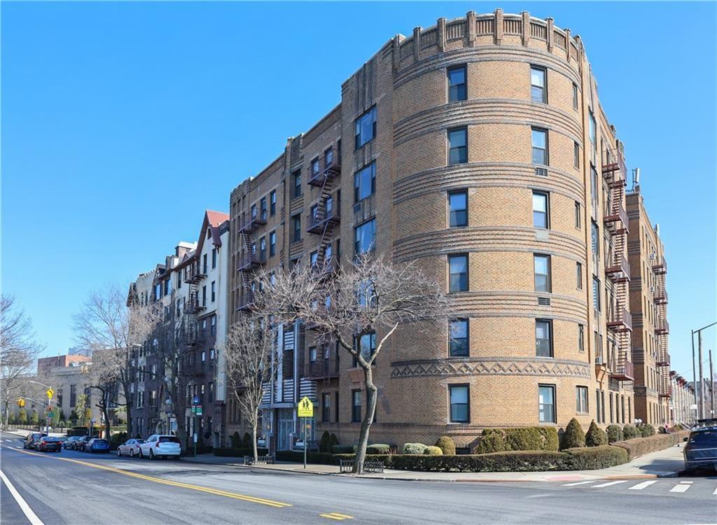 a front view of multi story residential apartment building with yard and traffic signal