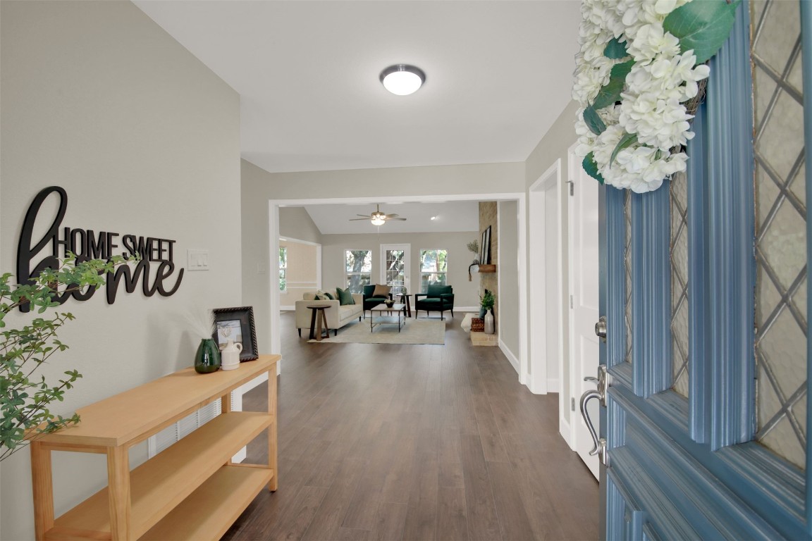 a view of a hallway with a dining table couches chandelier and wooden floor