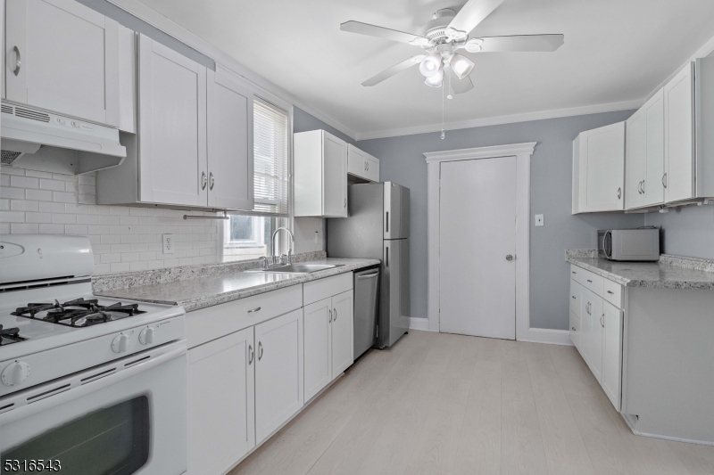 a kitchen with granite countertop a sink stainless steel appliances and cabinets