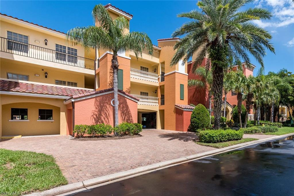 a front view of a multi story residential apartment building with yard and parking