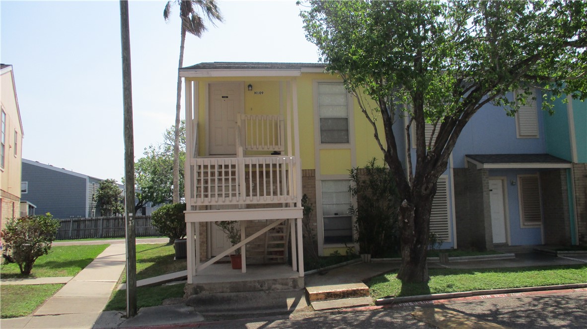 a view of a house with a yard and a large tree