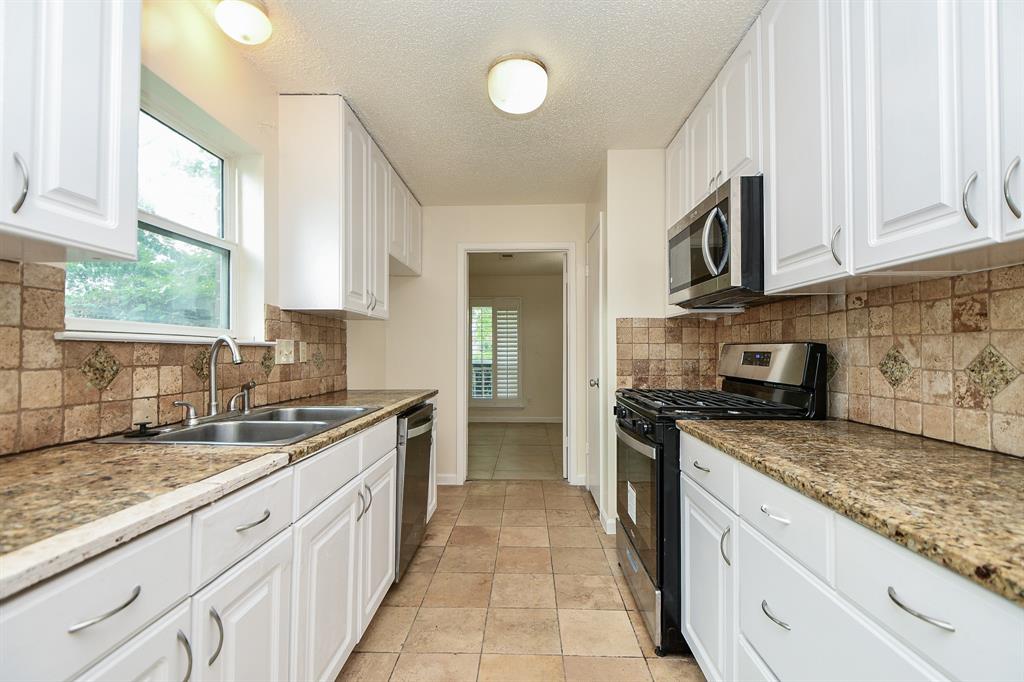 a large kitchen with granite countertop a sink dishwasher stove and cabinets