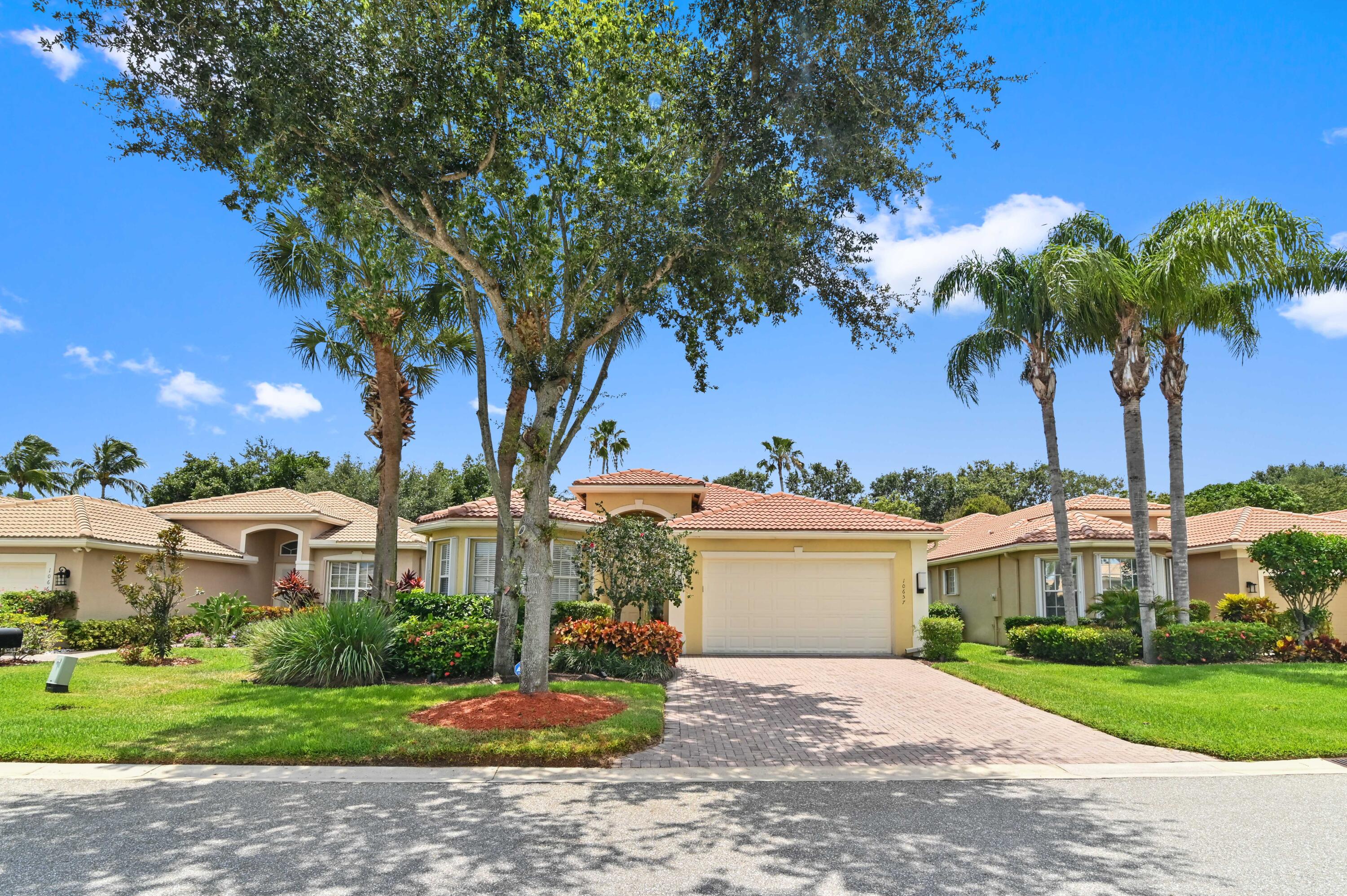 a front view of a house with a garden and trees