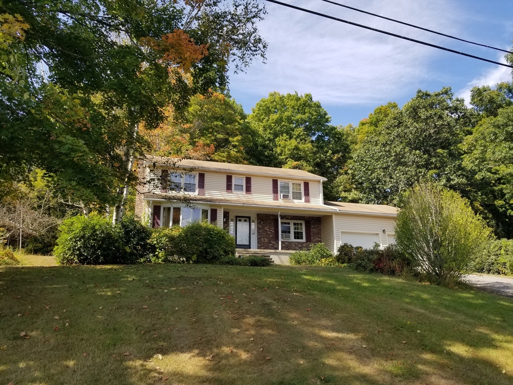 a front view of a house with a yard and trees