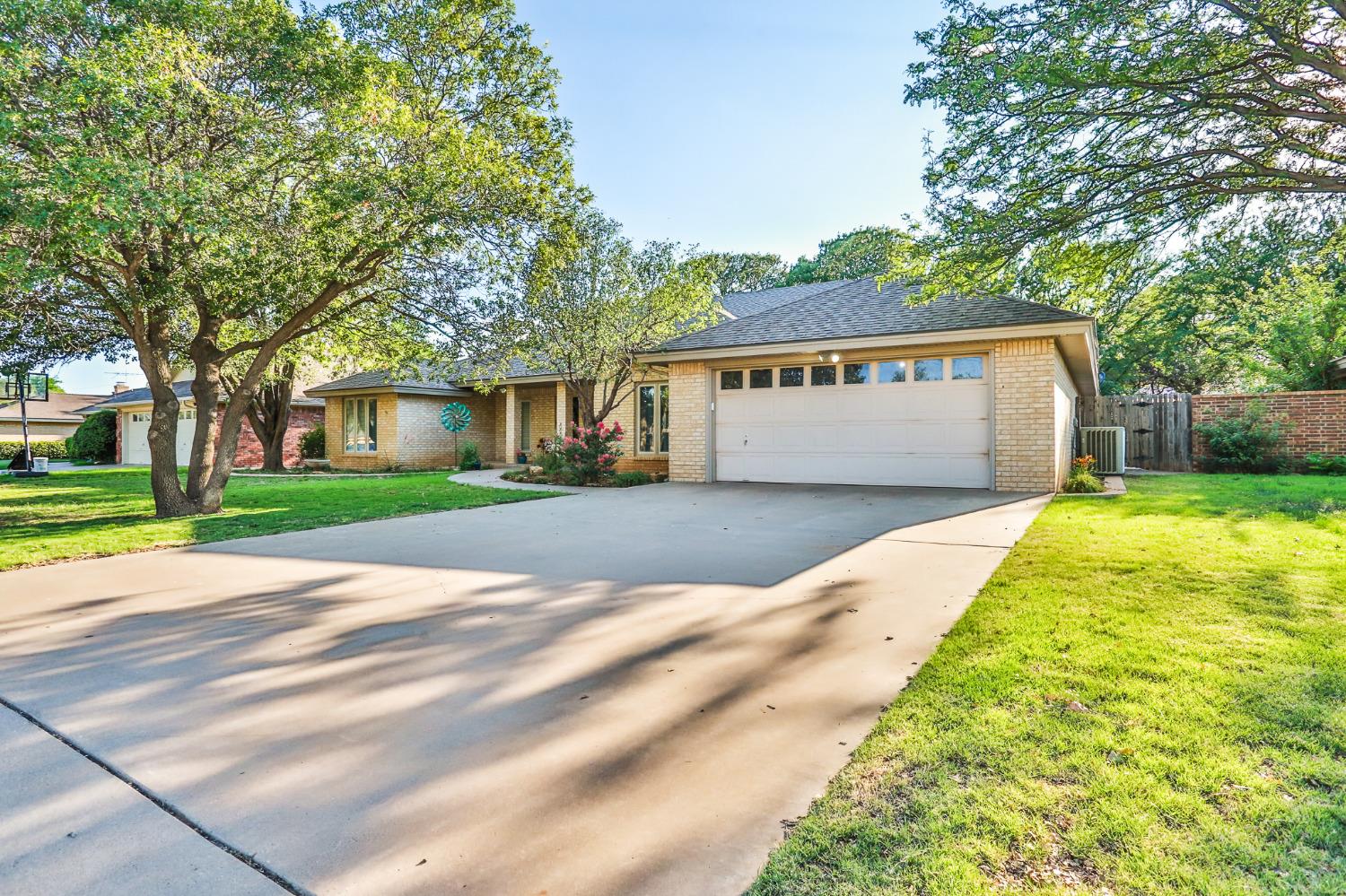 a view of a house with a big yard plants and large trees