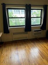 Empty room featuring radiator, light hardwood / wood-style flooring, and a wall mounted air conditioner