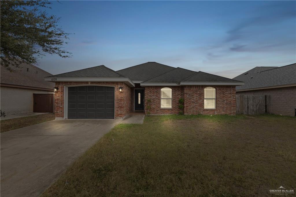 Single story home featuring a yard and a garage