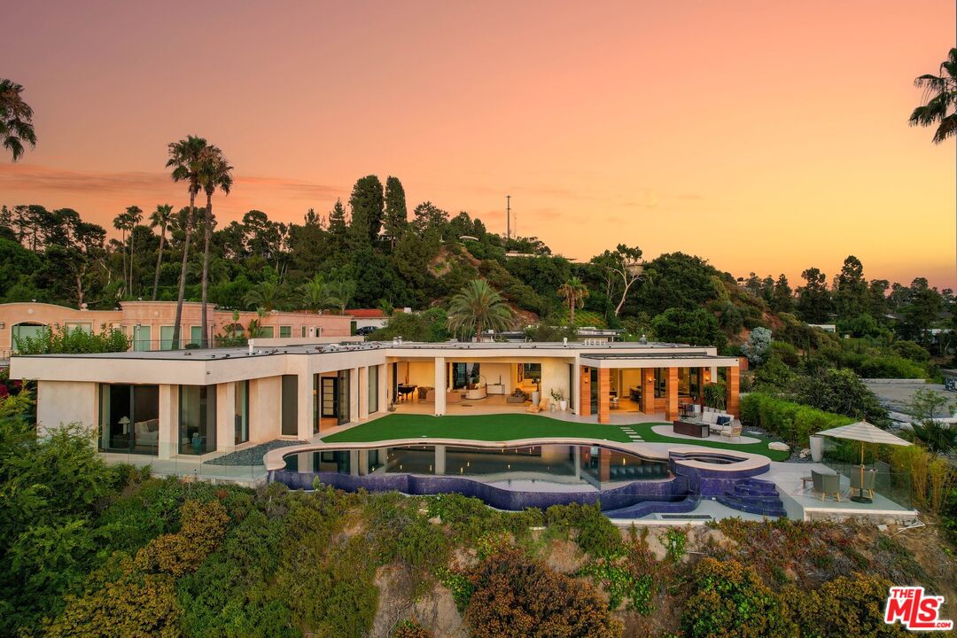 a view of a house with pool and trees in the background