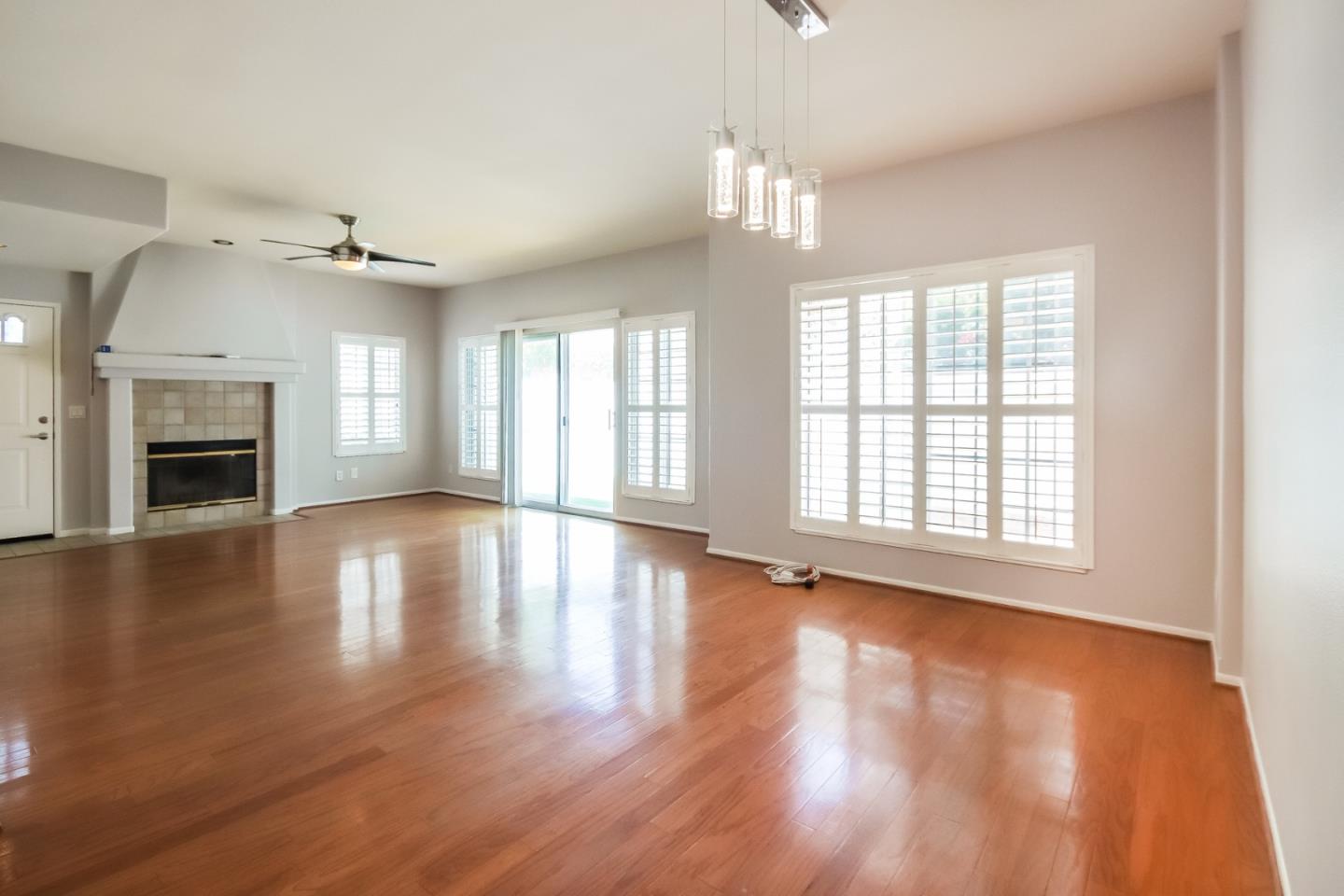 an empty room with wooden floor fireplace and windows