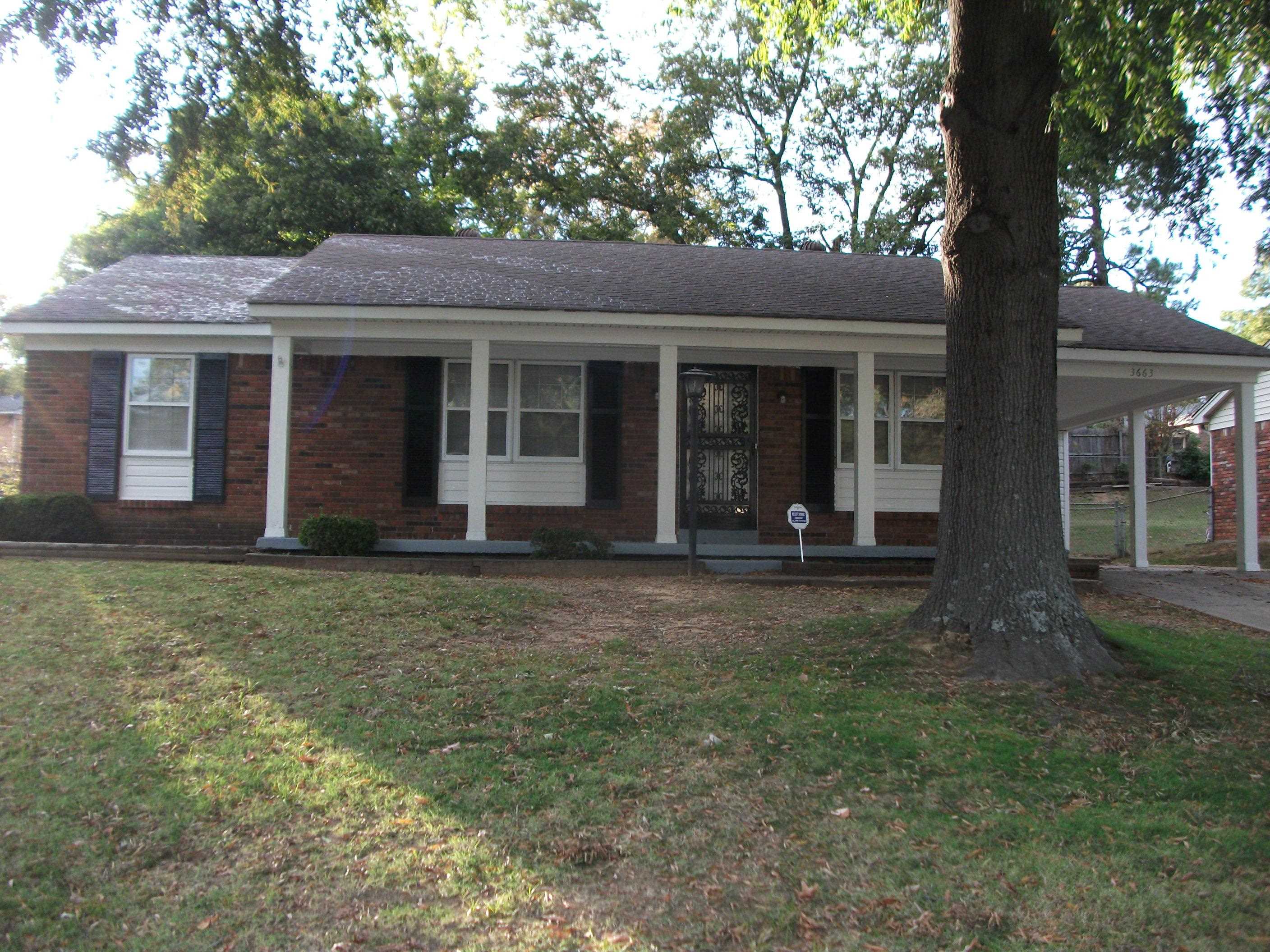 a view of a brick house with large windows and a large tree