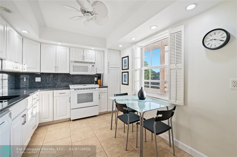 a kitchen with a dining table chairs and white cabinets