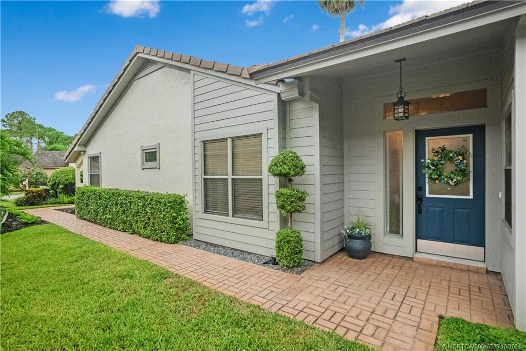 a front view of a house with a yard and potted plants