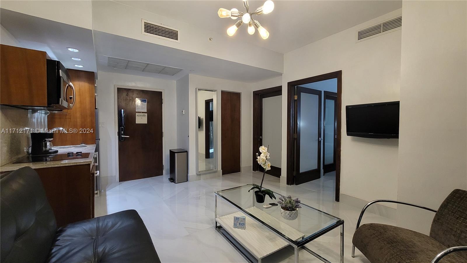 a living room with furniture a flat screen tv and kitchen view