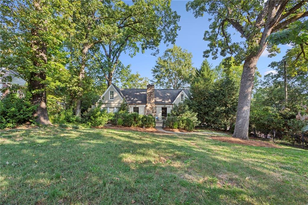 a view of a house with a big yard and large trees