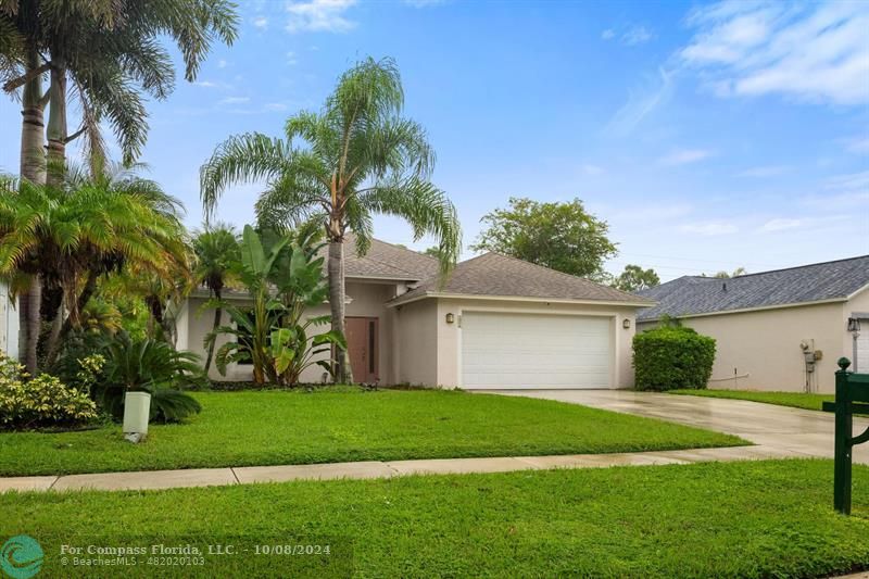 a front view of a house with a yard and palm trees