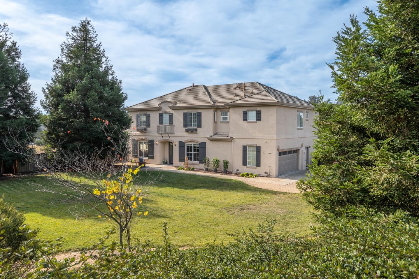 a view of a big house with plants and large trees