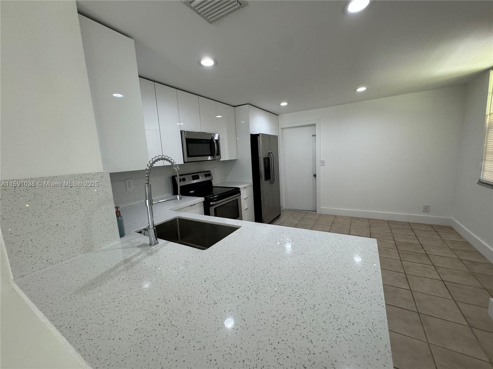 a kitchen with granite countertop a refrigerator and a sink