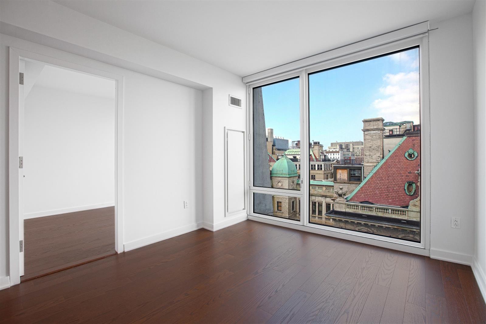 a view of an empty room with wooden floor and a window