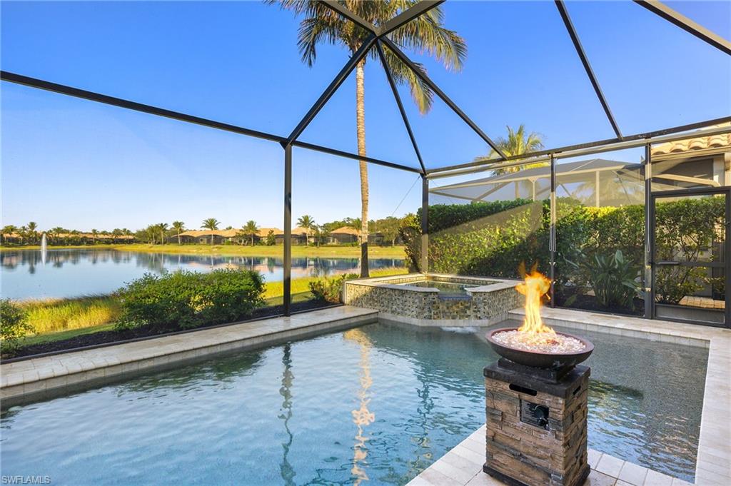 View of pool with glass enclosure, an in ground hot tub, a water view, and an outdoor fire pit