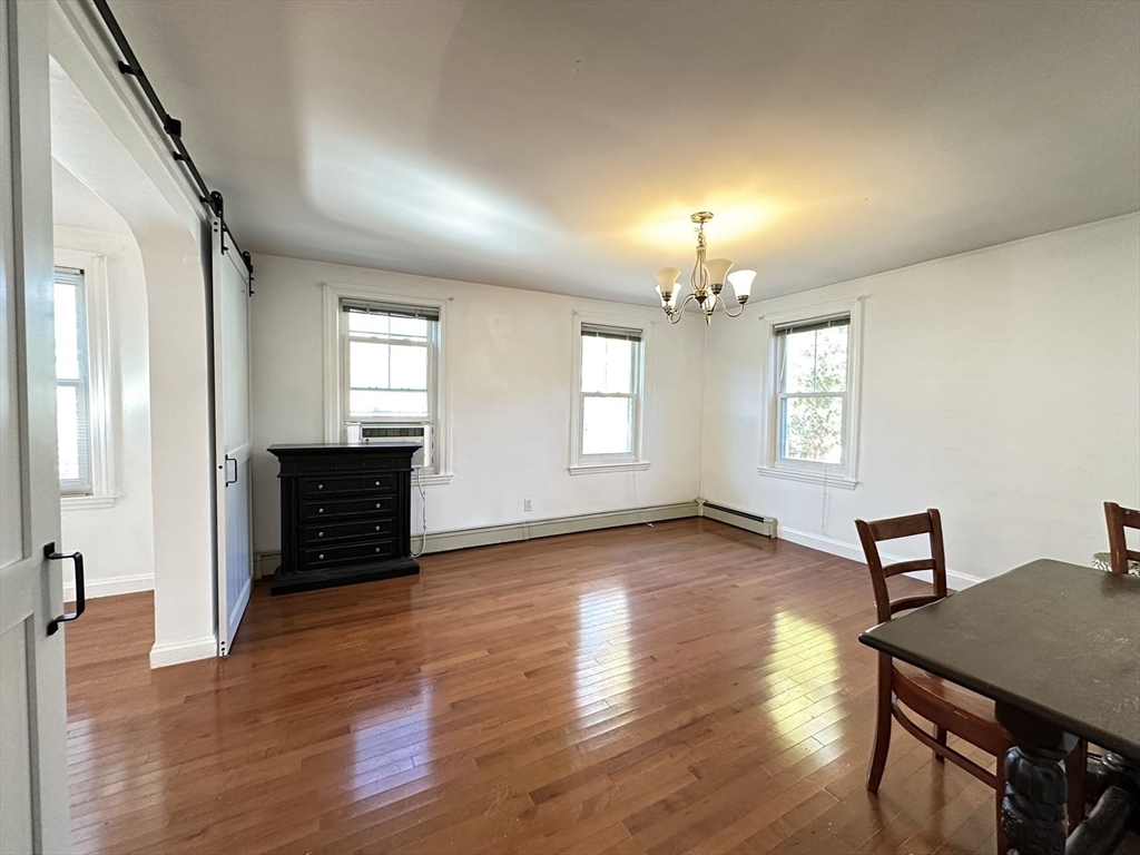 an empty room with wooden floor chandelier and windows