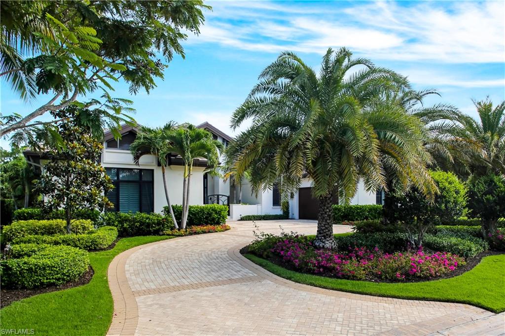 a front view of a house with a garden and trees