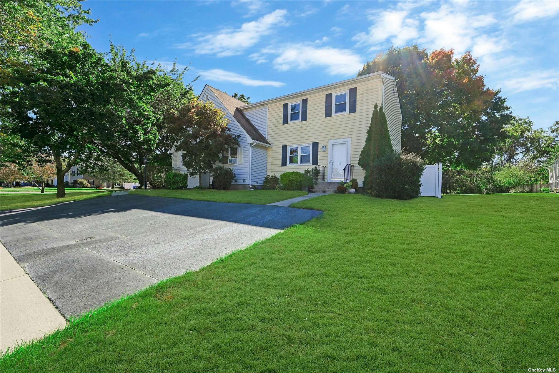 a view of a white house next to a yard and a road