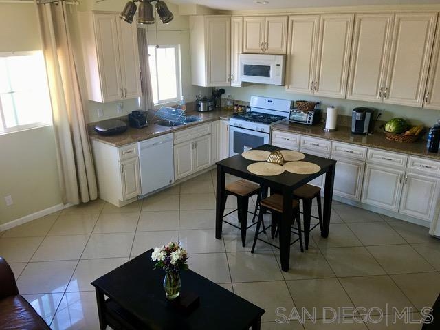 a kitchen with stainless steel appliances granite countertop a table chairs sink and cabinets