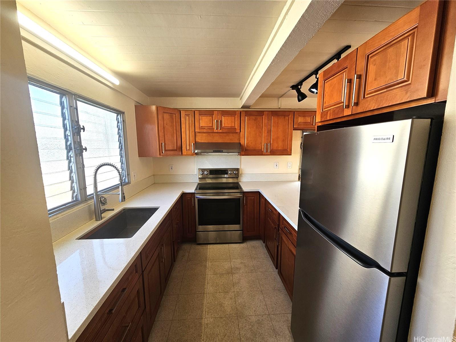 a kitchen with granite countertop a refrigerator a sink a stove and cabinets