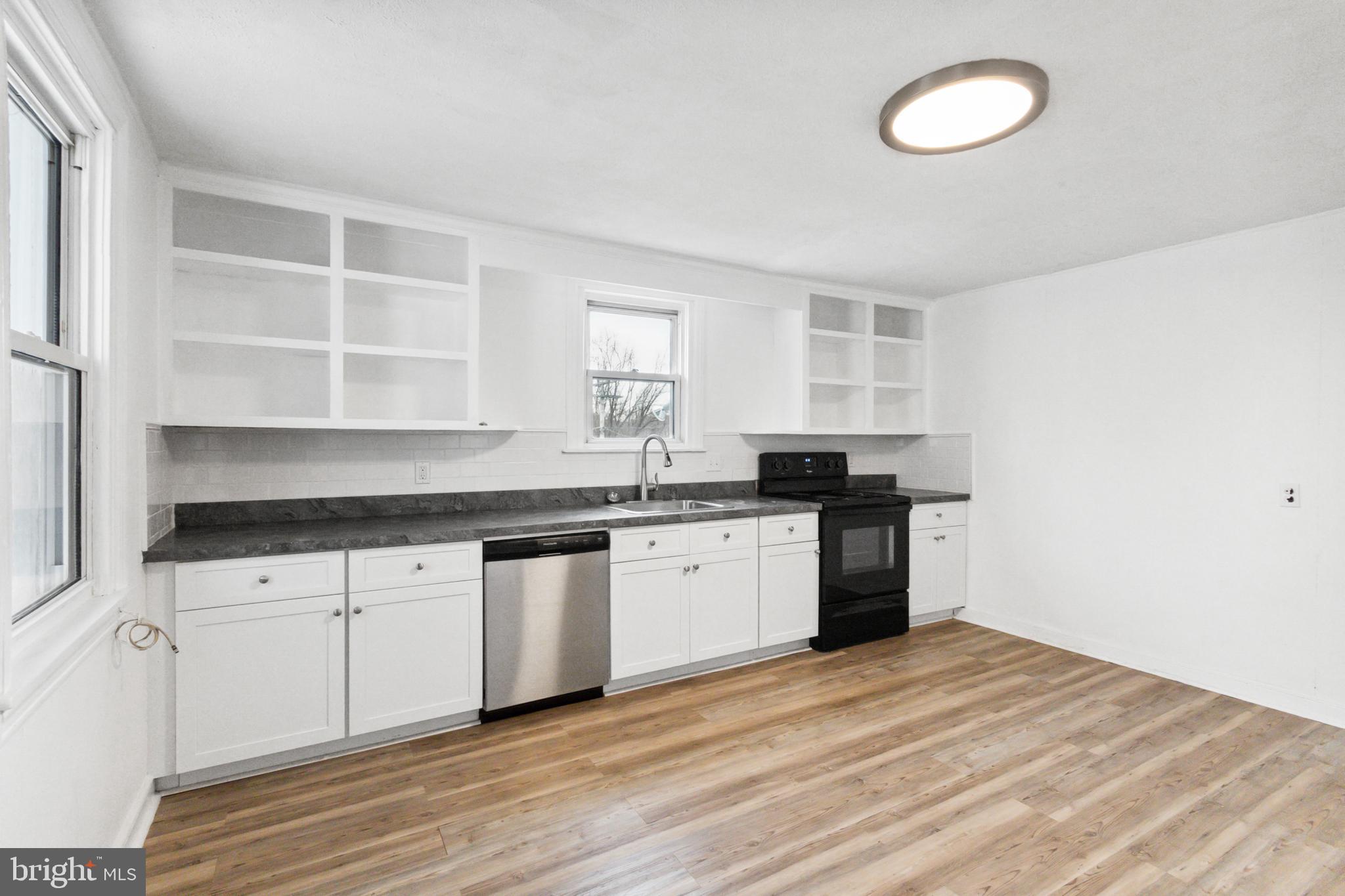 a kitchen with granite countertop a sink cabinets and stainless steel appliances