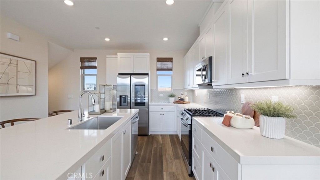 a kitchen that has a lot of cabinets a sink and wooden floor