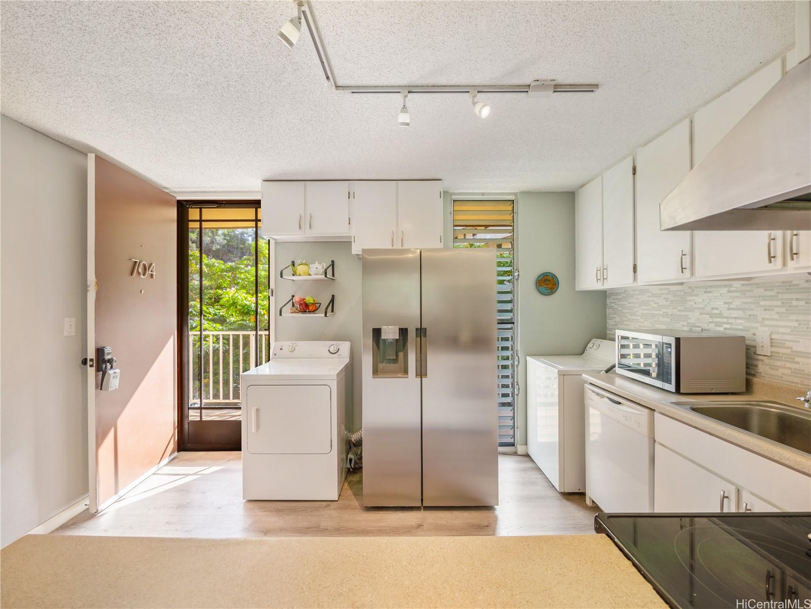 a kitchen with stainless steel appliances granite countertop a refrigerator a stove and a sink