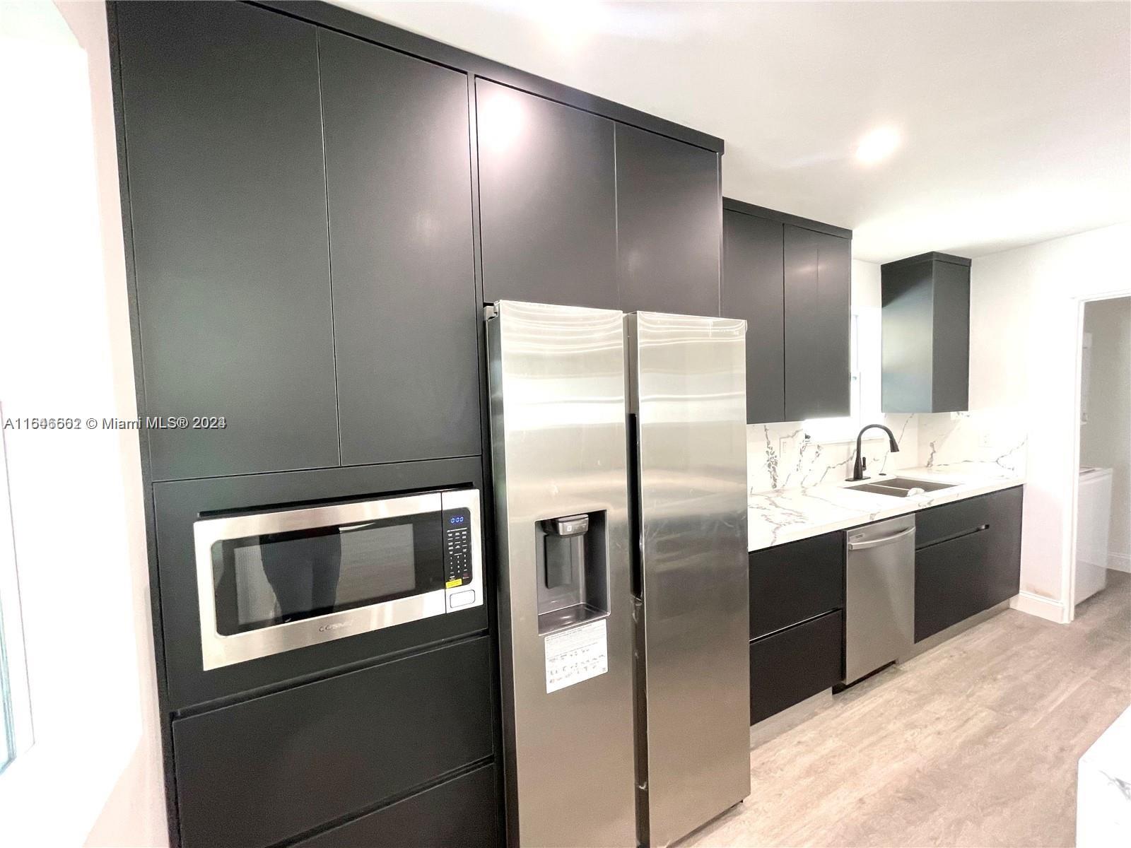 a kitchen with stainless steel appliances kitchen island granite countertop a refrigerator and a sink