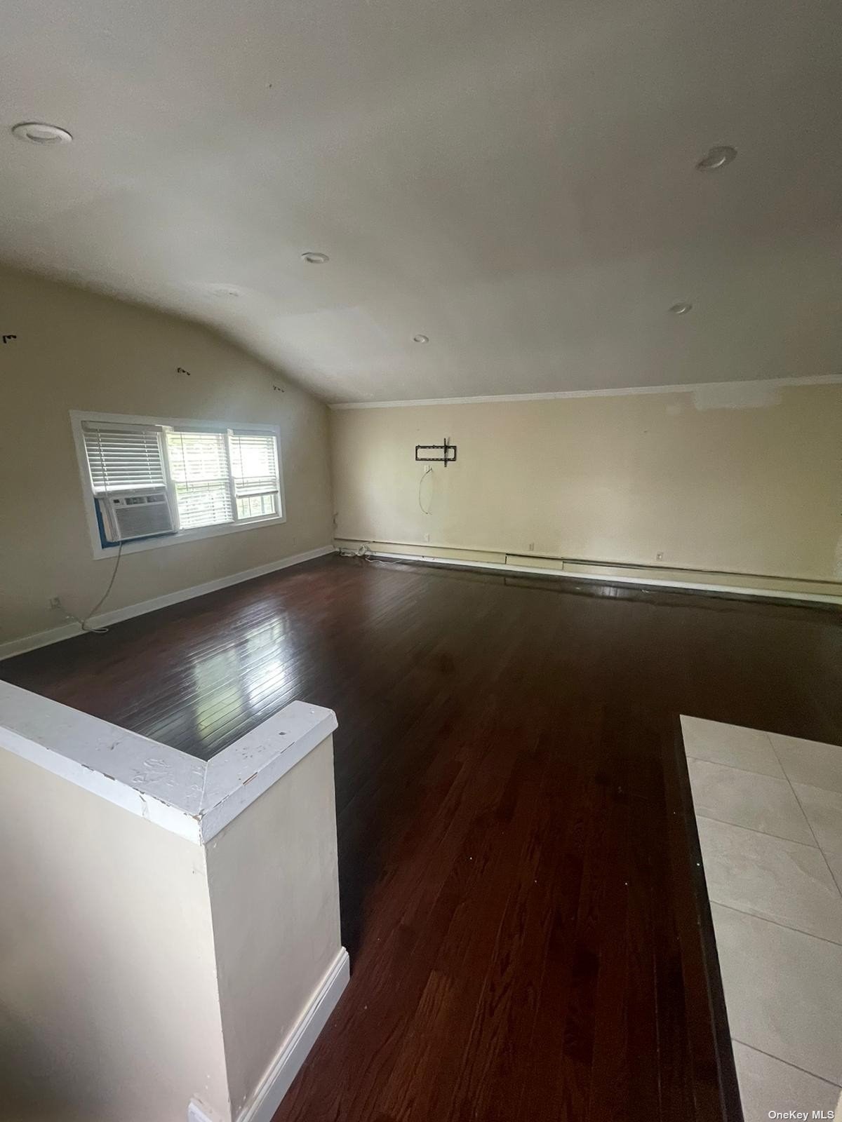 a view of an empty room with window and wooden floor