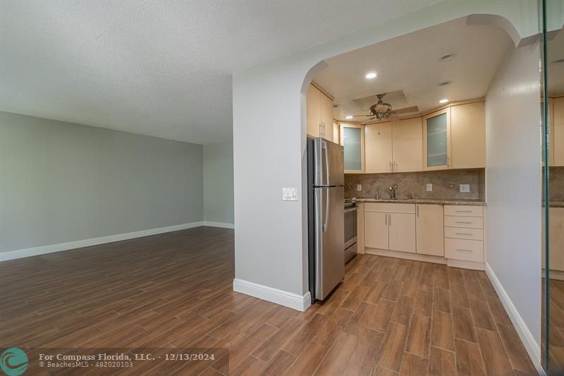 a view of a kitchen with a sink and dishwasher a refrigerator with wooden floor