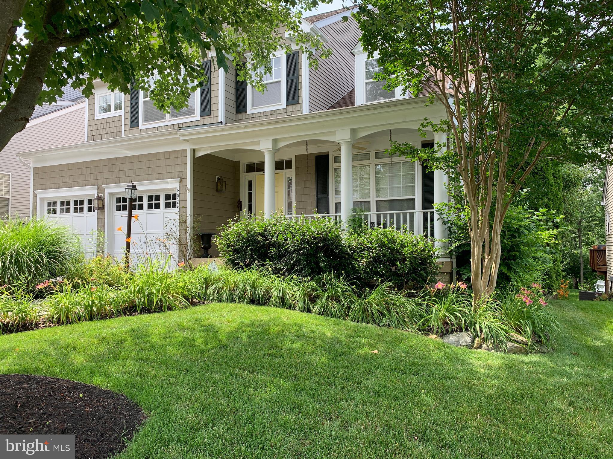 a view of a white house next to a yard with big trees