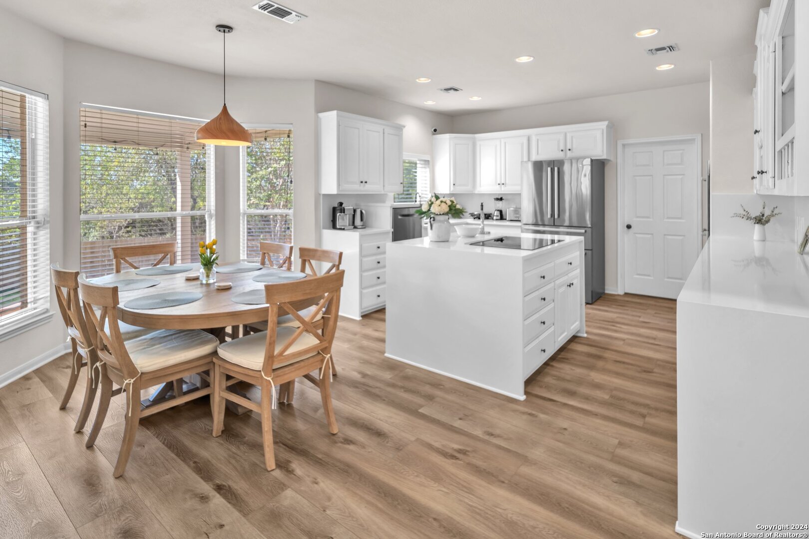 a kitchen with stainless steel appliances kitchen island granite countertop a table chairs and a wooden floor