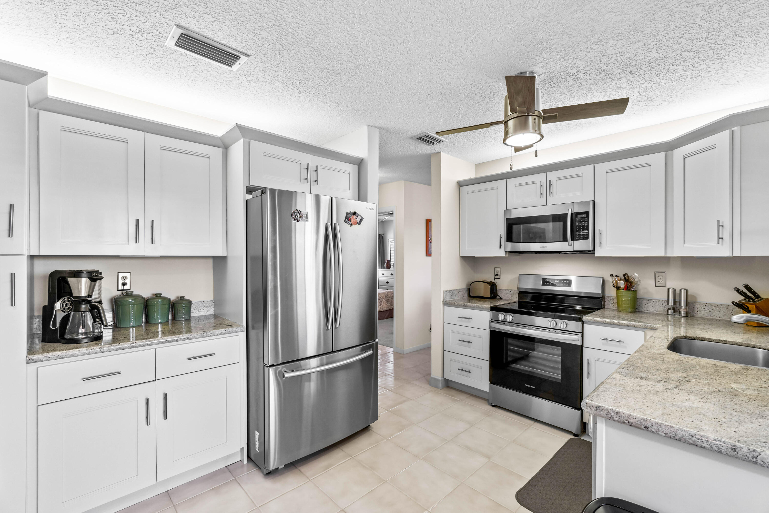 a kitchen with stainless steel appliances granite countertop a refrigerator a stove a sink and white cabinets