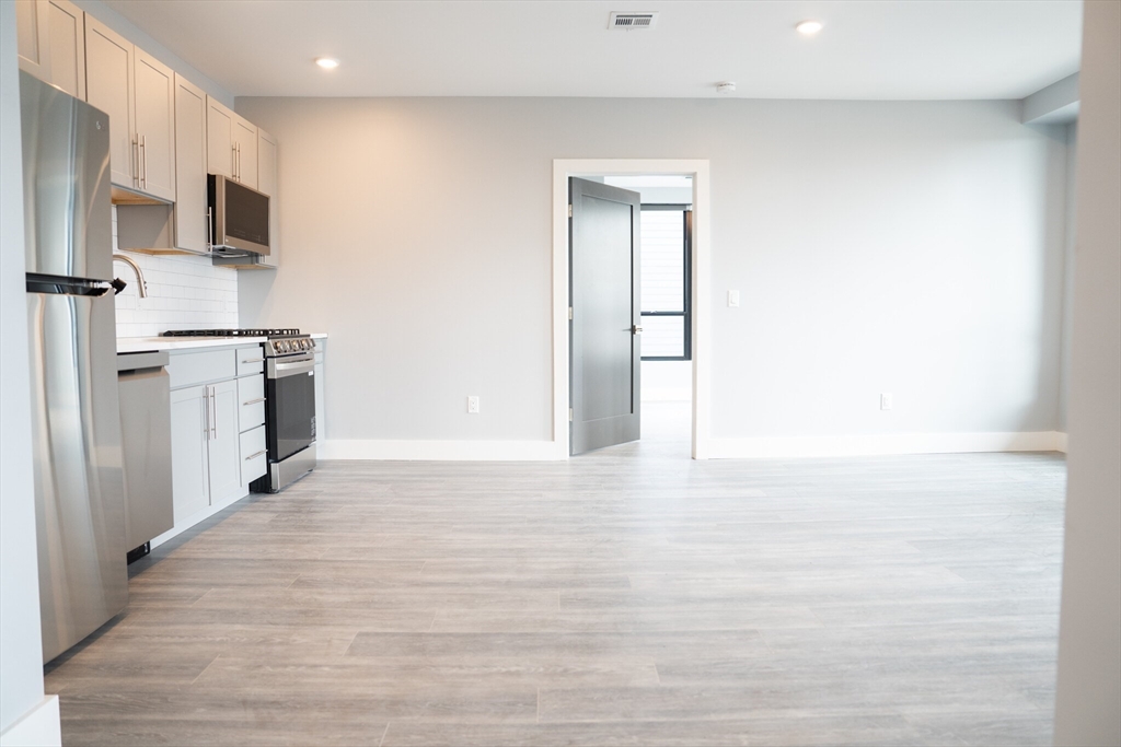 a view of a kitchen with stainless steel appliances wooden floor and a window