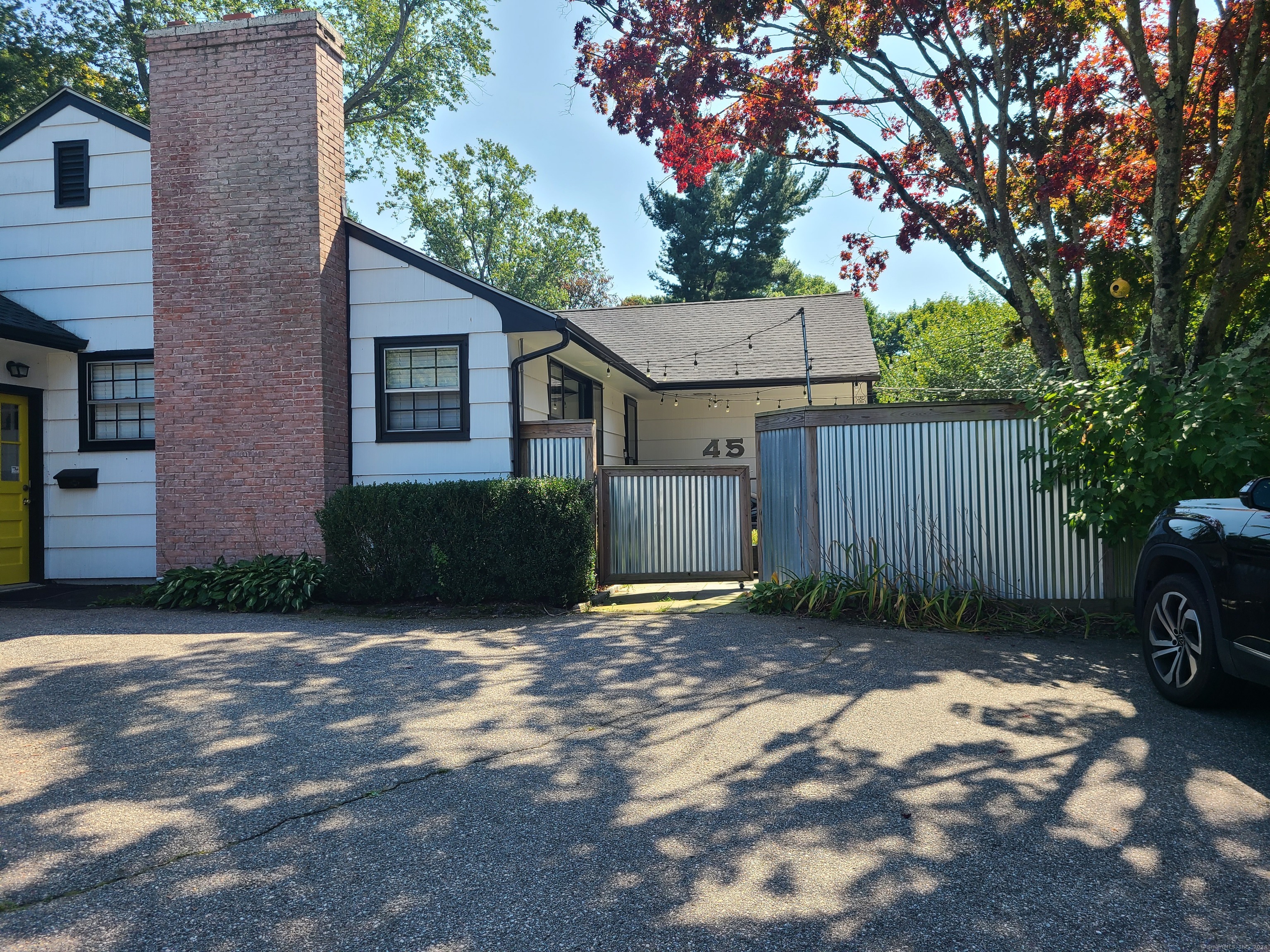 a view of a house with a small yard plants and a large tree