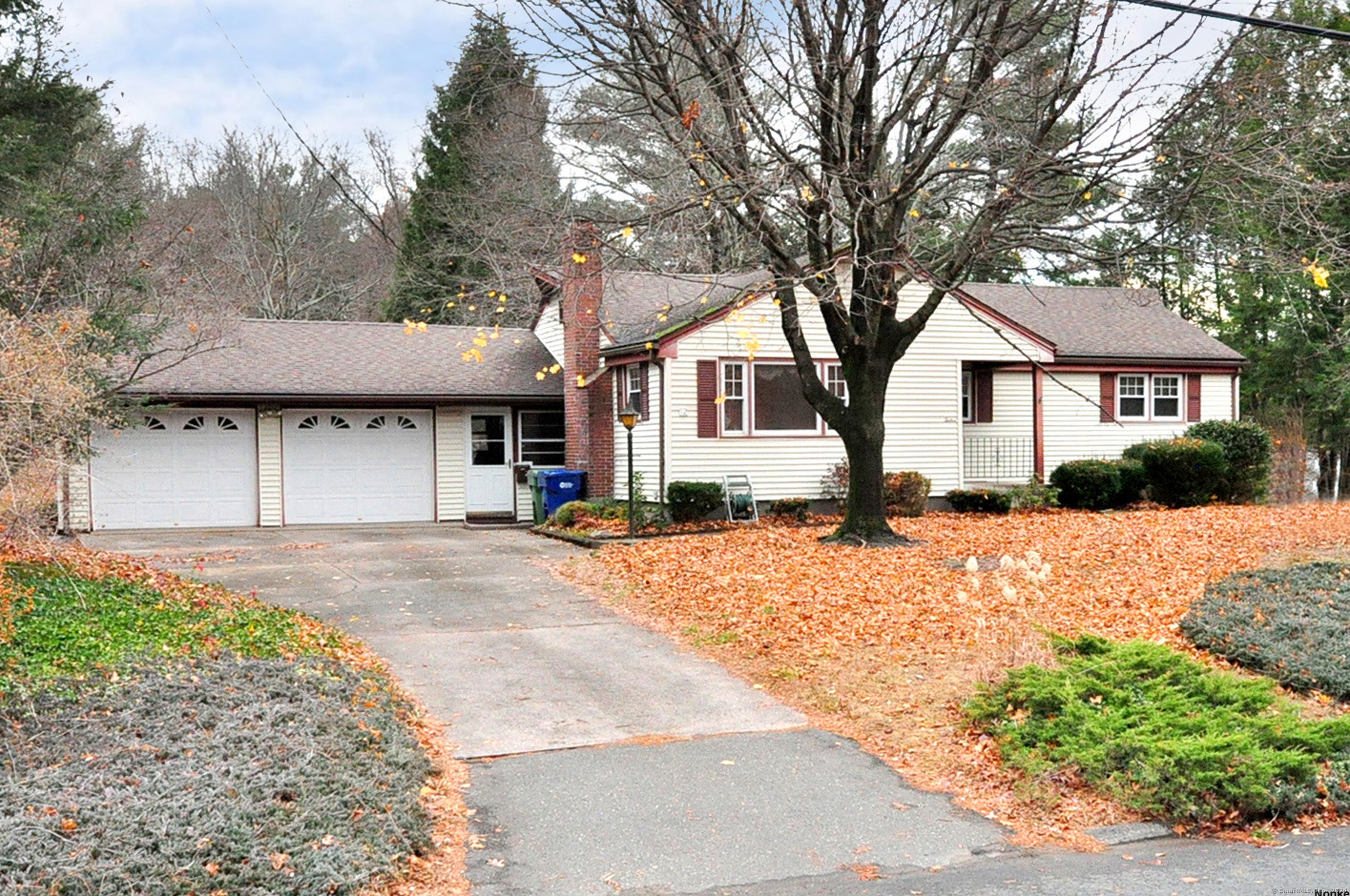 a front view of a house with a dirt yard and a large tree