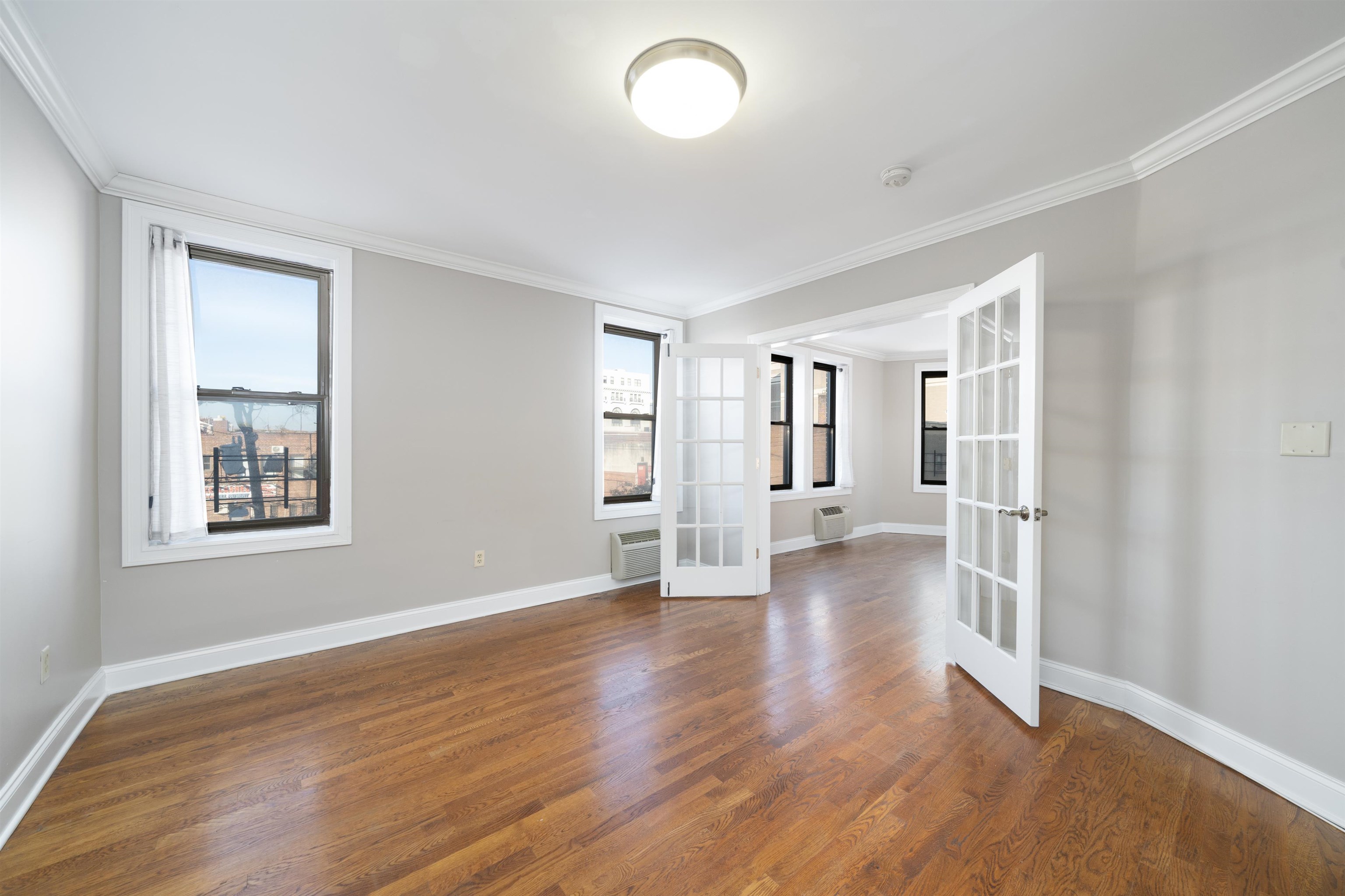 an empty room with wooden floor and windows