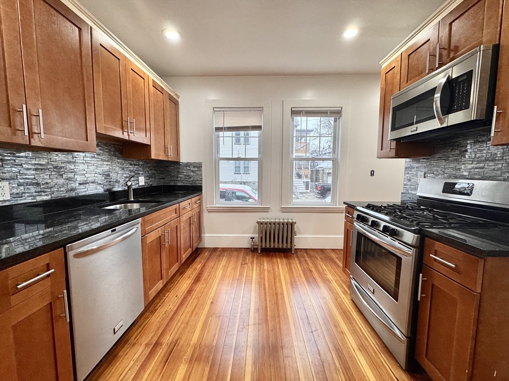 a kitchen with stainless steel appliances a stove a sink cabinets and a wooden floor