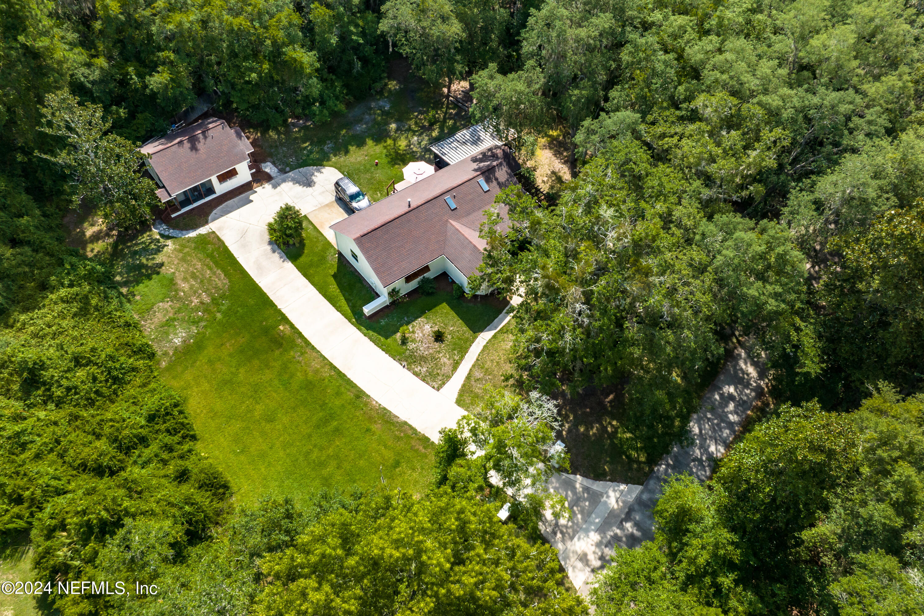 an aerial view of residential house with outdoor space and trees all around