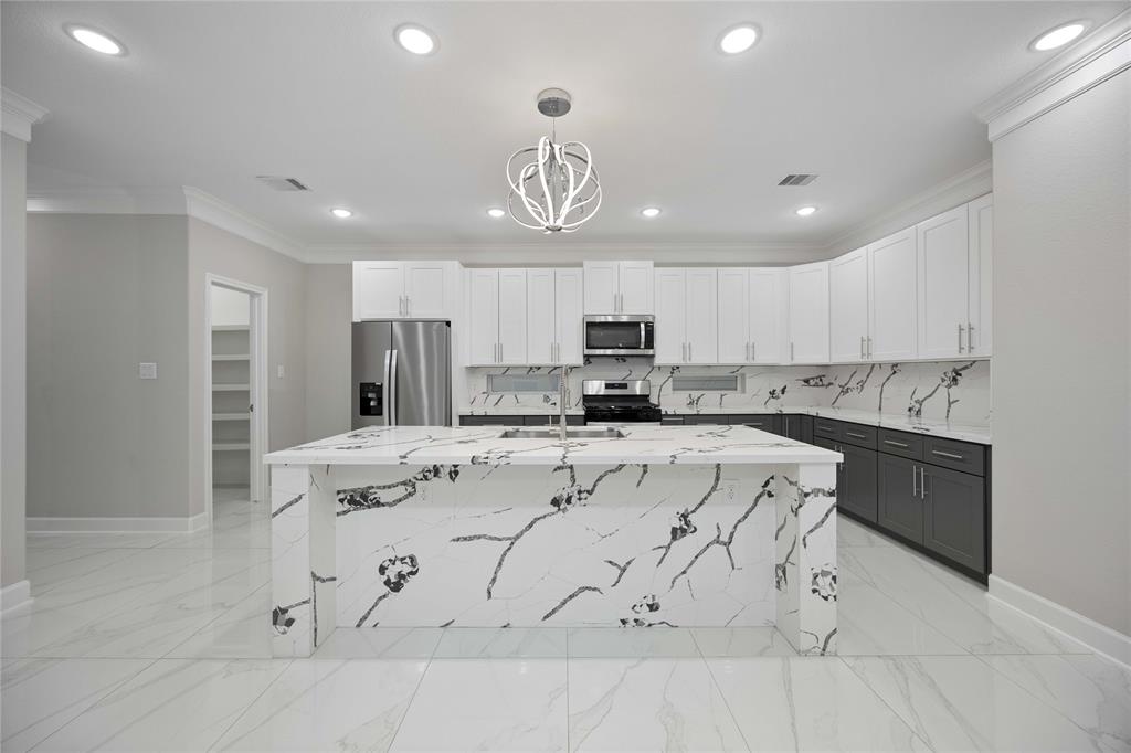 a kitchen with stainless steel appliances a stove a sink a center island and cabinets