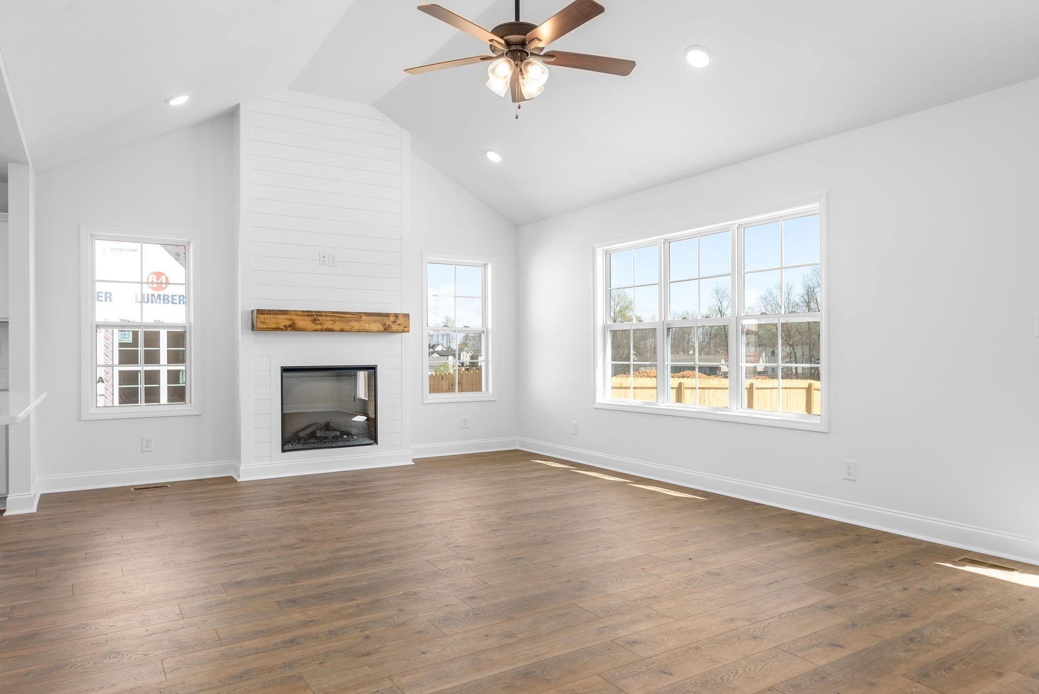 an empty room with windows fireplace and wooden floor