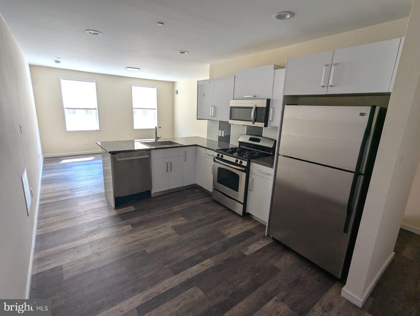 a kitchen with granite countertop a refrigerator stove top oven and sink