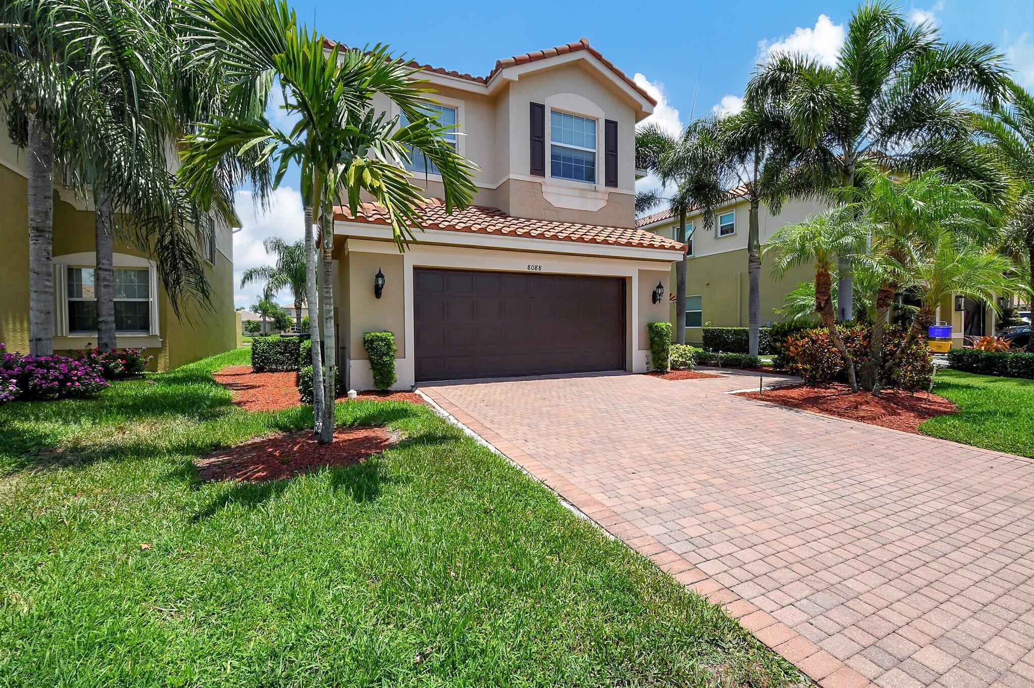 a front view of a house with a yard and palm trees