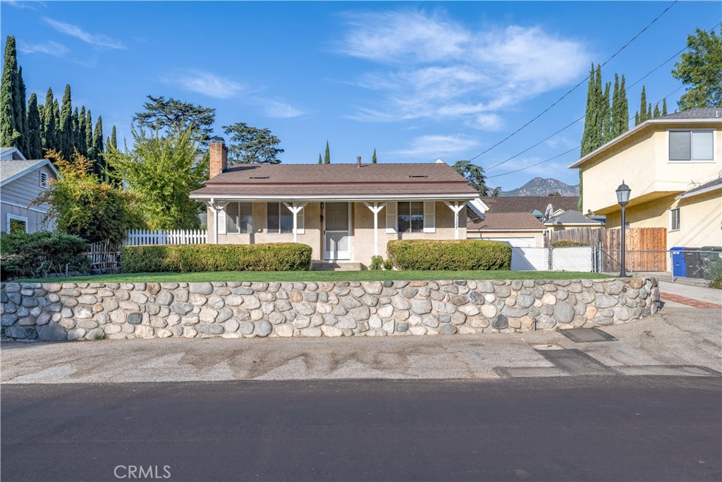 a front view of a house with a yard and a lot of trees in the background