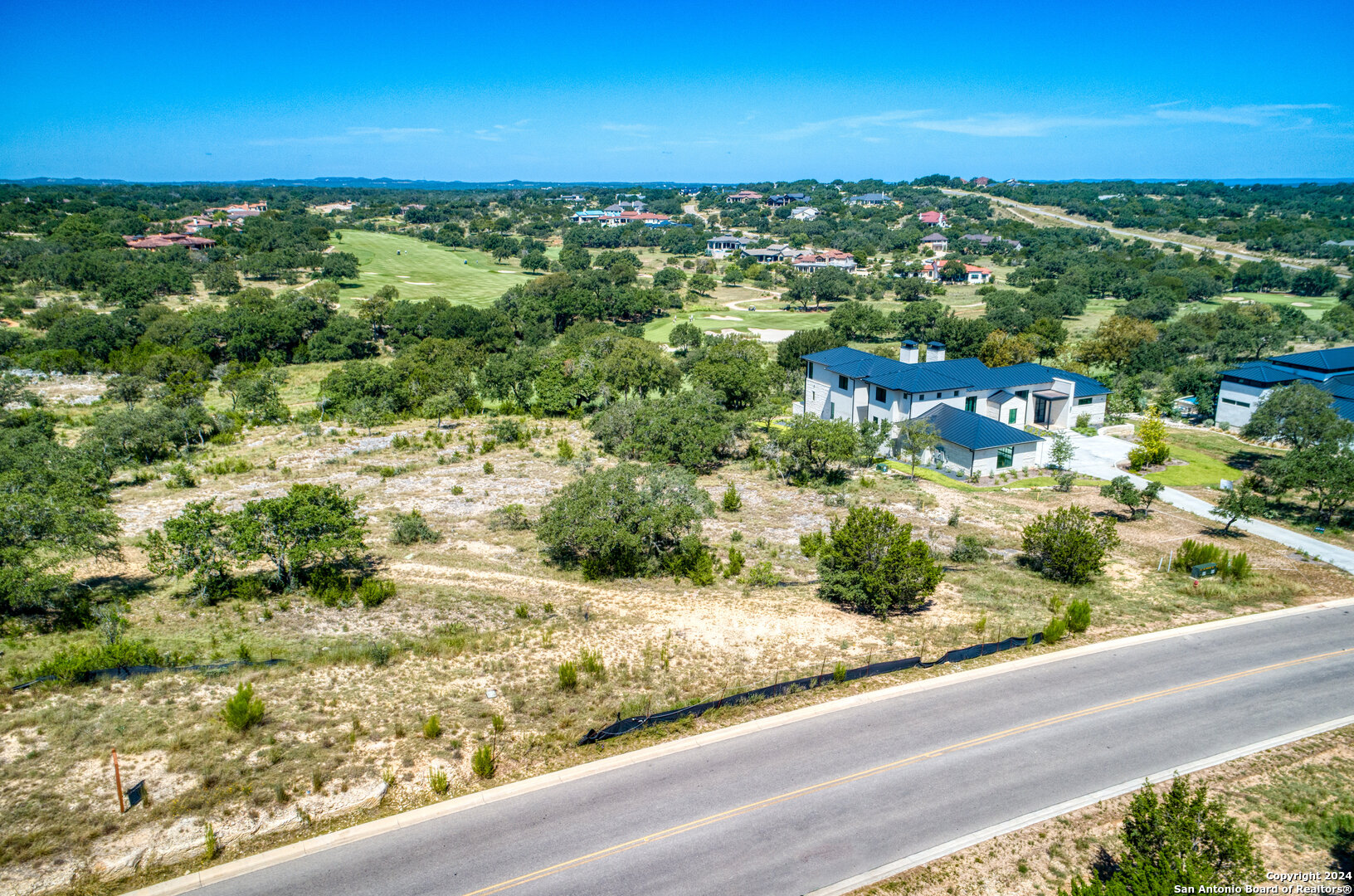 an aerial view of residential houses with outdoor space and trees